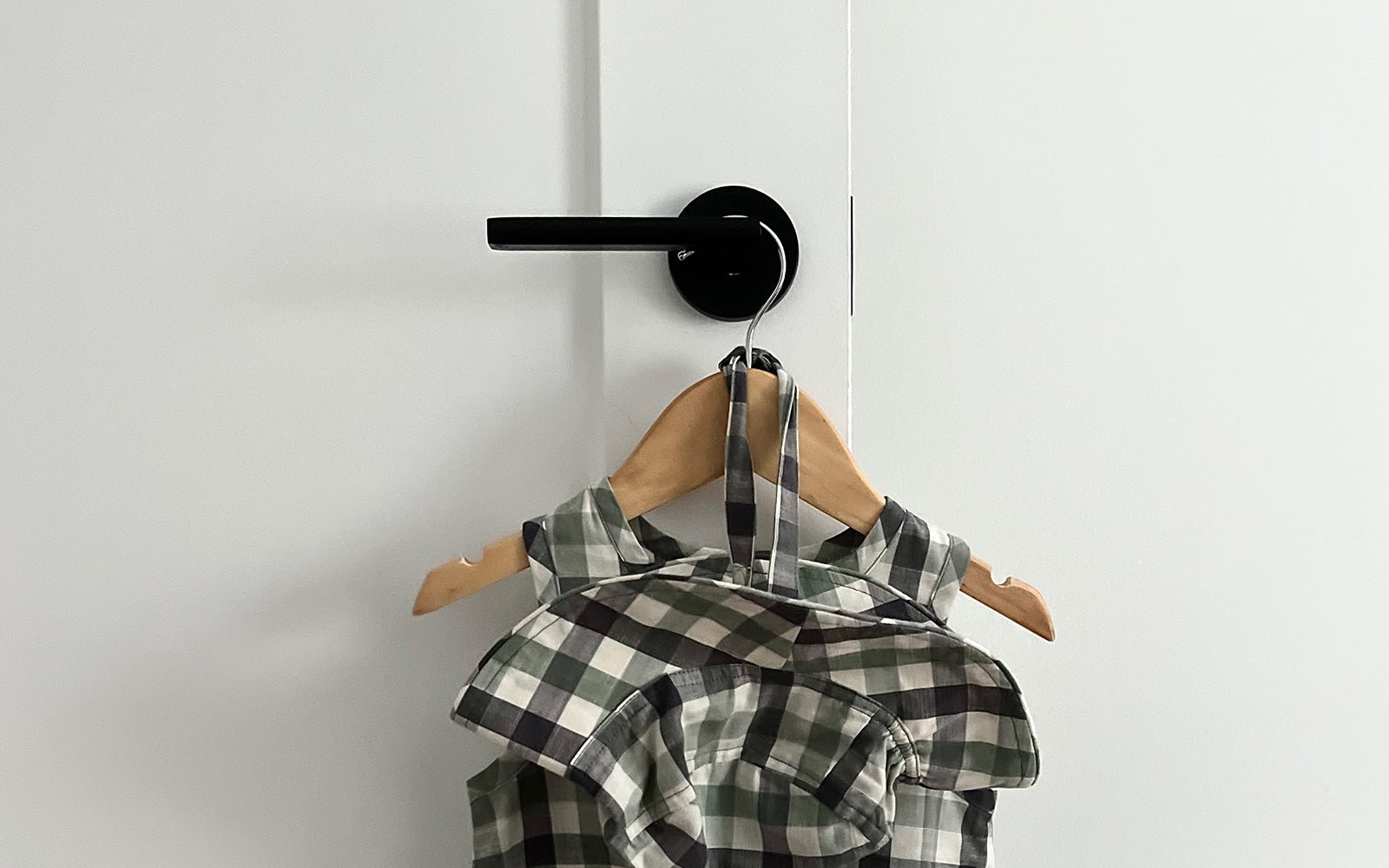 white bedroom door with black modern hardware from viaggio with a cute toddler girl outfit hanging on a wood hanger